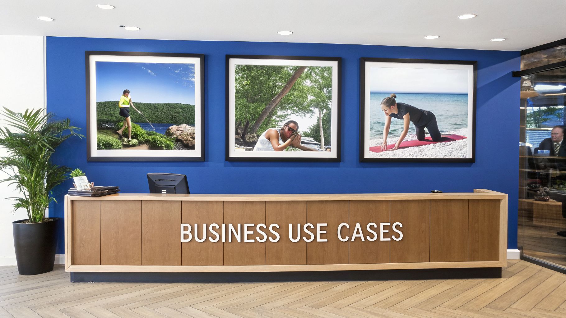 Modern office reception with a wooden desk featuring 'Business Use Cases' text, blue wall, and framed lifestyle artwork.