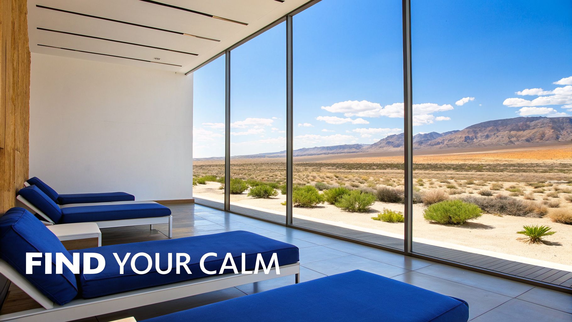 Modern indoor relaxation area with blue lounges, offering expansive desert and mountain views through large windows.